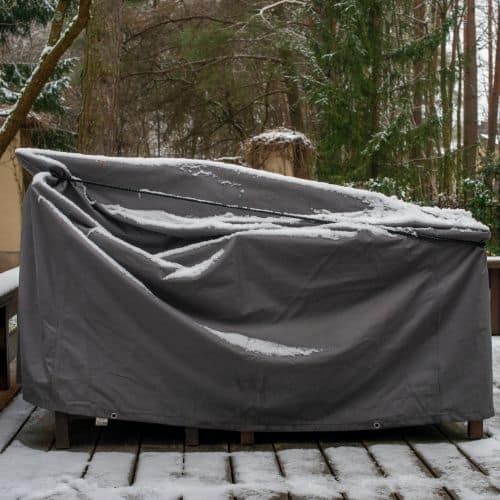 Outdoor furniture covered in a tarp in the winter.