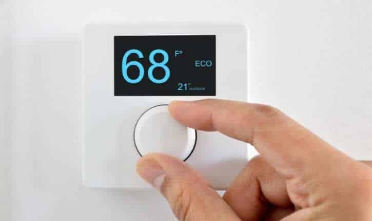 Person adjusting heat setting on a thermostat.