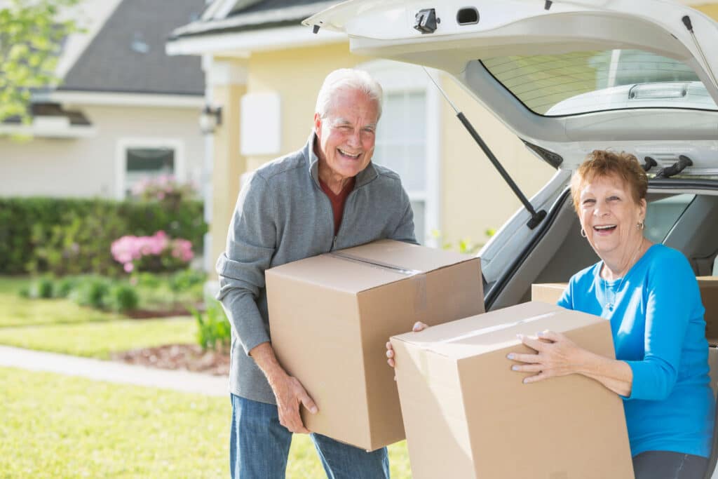 Senior couple moving boxes into a downsized home. 