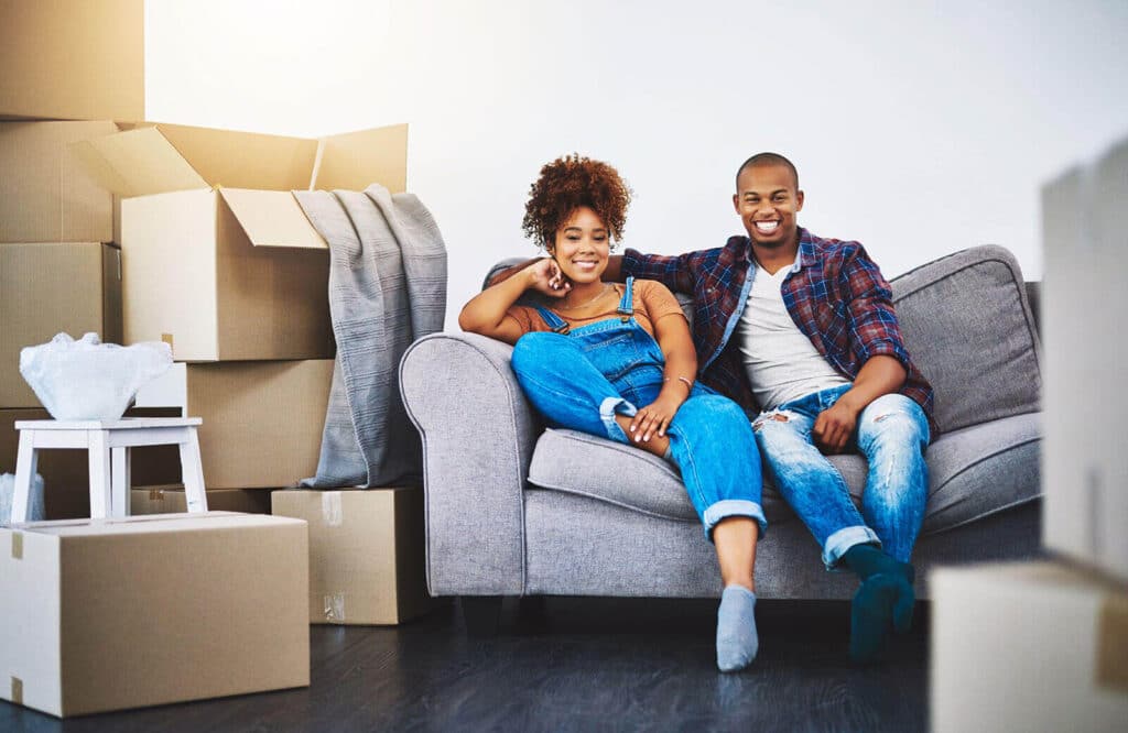 Couple sitting on a couch near their packaged furniture