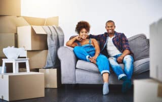 Couple sitting on a couch near their packaged furniture