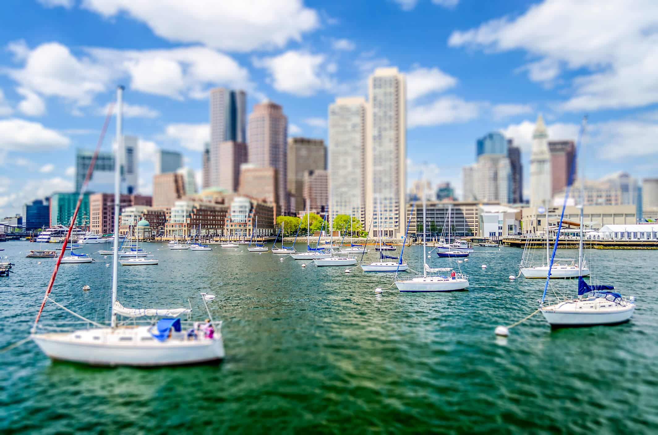 Boats floating in the Boston bay with view of the city skyline.
