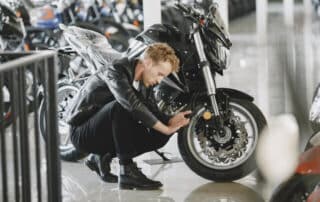 Person inspecting a motorcycle in storage.