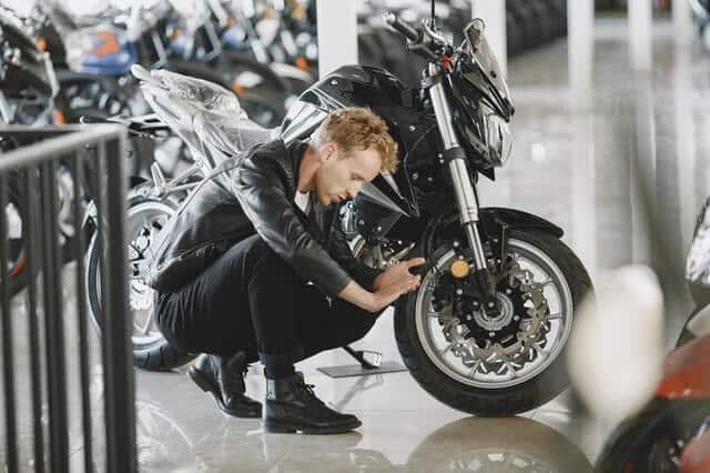 Person inspecting a motorcycle in storage.