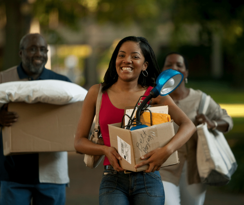 Student moving onto a college campus holding a packed box.