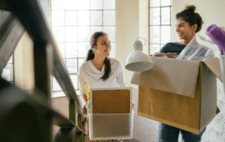 Two students moving packed boxes into their dormitory.