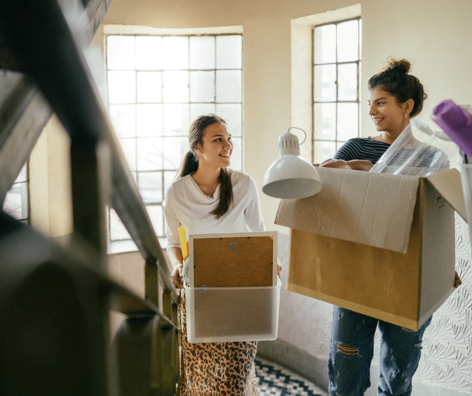 Two students moving packed boxes into their dormitory.