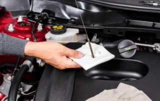 Person checking motor oil in car engine.