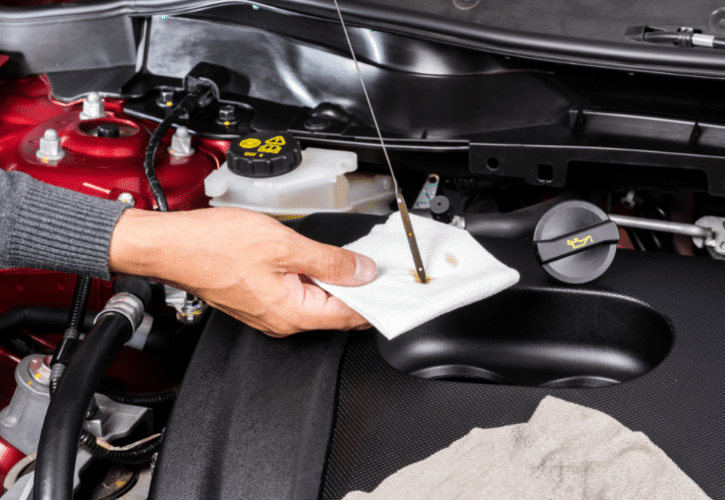 Person checking motor oil in car engine.