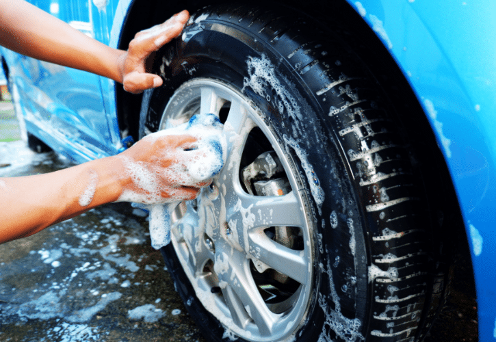 Hand washing car tires with soap.