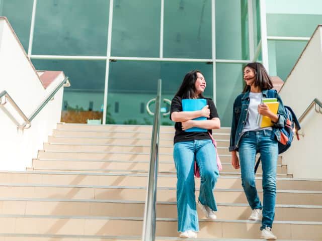 two college students walking down the steps at a building