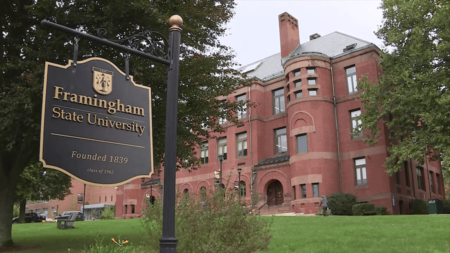 black sign that reads 'framingham state university founded 1839, class of 1962' with a tall brick building in the background.