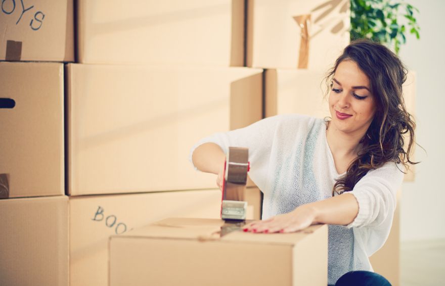 Woman sealing a cardboard box with tape.