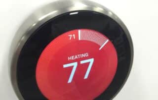 Red, round thermostat displaying the numbers '77' in white.