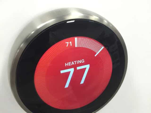 Red, round thermostat displaying the numbers '77' in white.