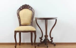 antique chair and side table sitting against a white wall