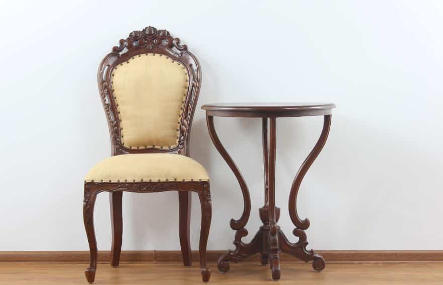 antique chair and side table sitting against a white wall