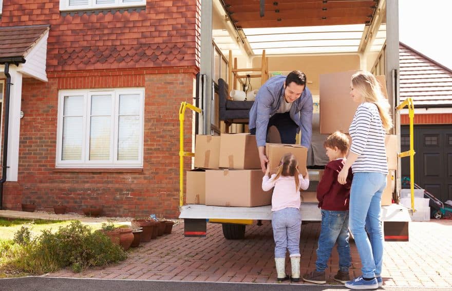 man, woman and child putting cardboard boxes into the back of a moving truck at their home