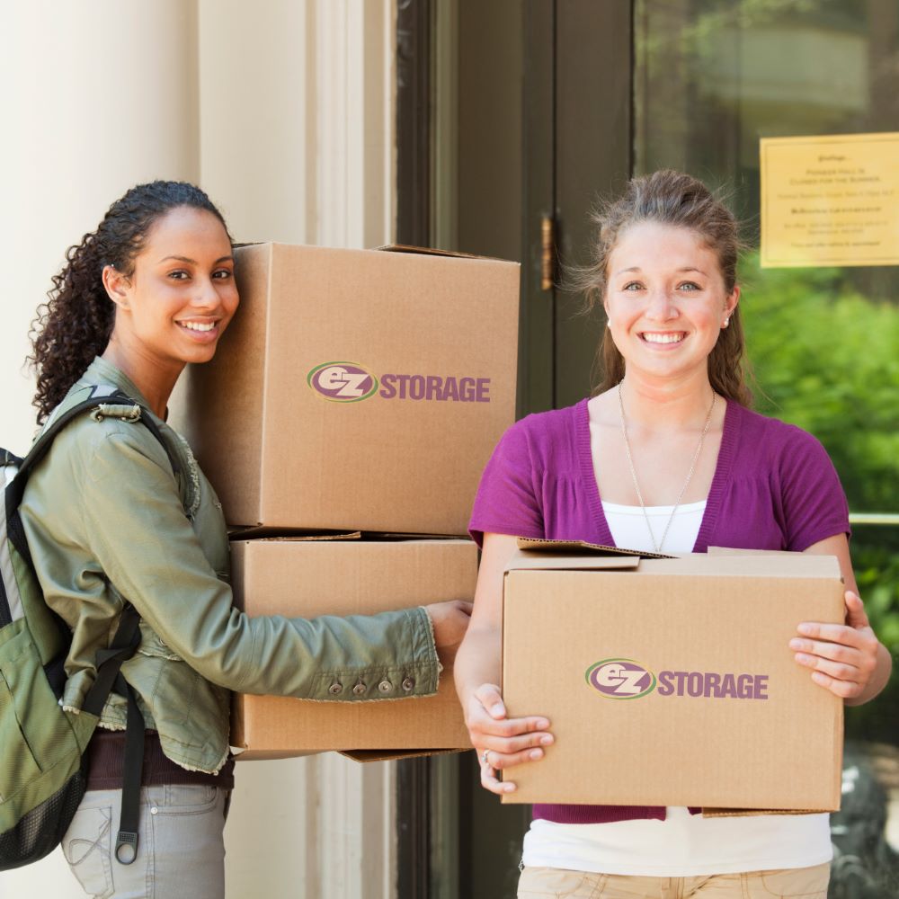 two college students holding moving boxes with the ez storage logo on them