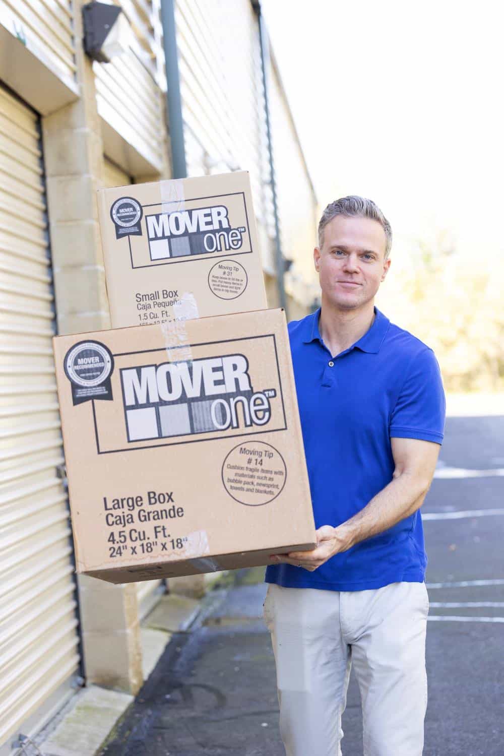 person in a blue storage carrying boxes to self storage