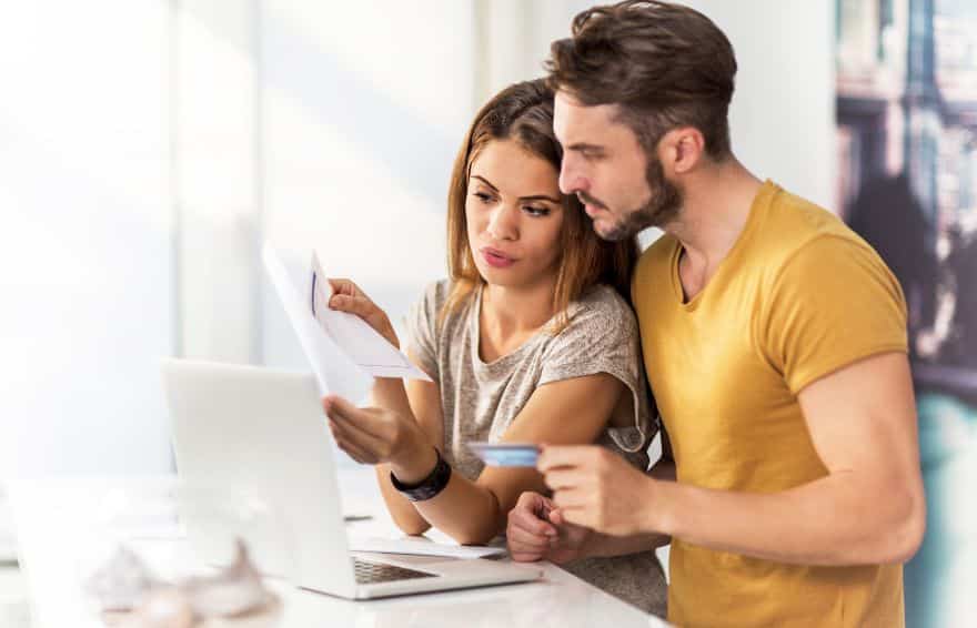 a couple looking at their finances on paper and a laptop